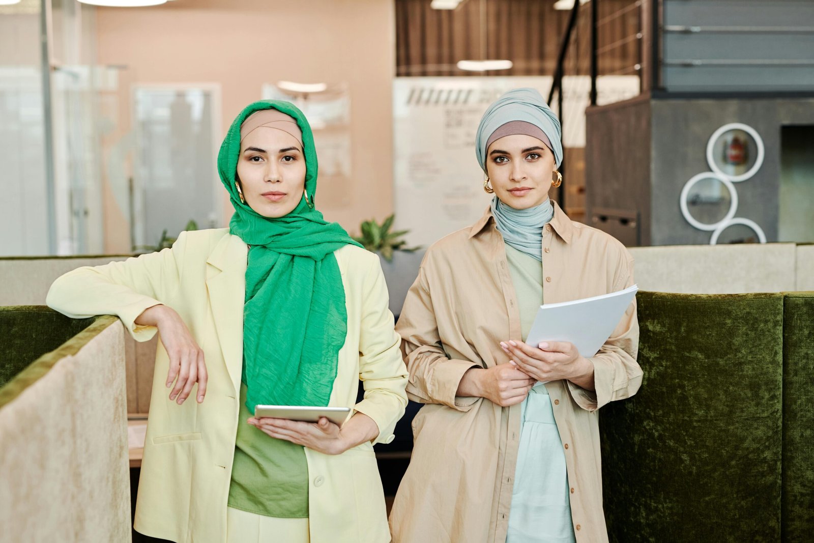 Two fashionable women in hijabs working together in a modern office environment.